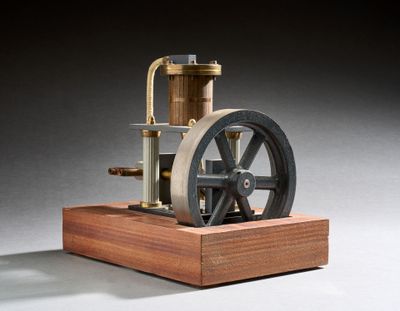 une petite maquette de machine à vapeur posée sur un socle en bois