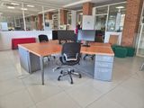 a desk with two computer monitors and a chair in the middle of the room