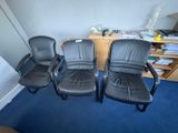 trois fauteuils de bureau en cuir noir dans un coin de la pièce