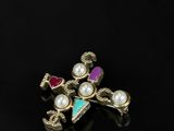a close up of a cross with pearls on a black surface
