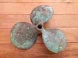 a bronze propeller sitting on a wooden floor