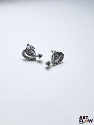 paire de boucles d'oreilles en argent ornées de cristaux verts sur fond blanc