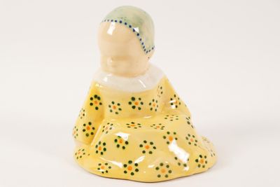 a small ceramic figurine of a woman sitting on the ground