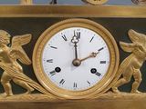 a gold clock with angels and a carriage on top of it