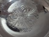 a silver plate with a design on it on a table