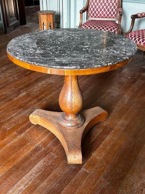 une table avec un plateau en marbre posée sur un parquet