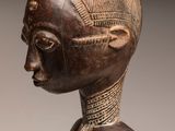 an image of a wooden statue of a woman with a hat on her head