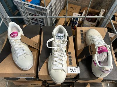 trois paires de baskets blanches posées sur des cartons