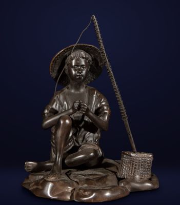 a bronze statue of a boy sitting on a rock with a fishing pole