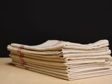 stack of folded linens on a wooden table against a black background