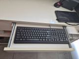 un clavier et une souris posés sur un bureau, à côté d'un écran