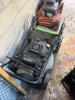 two lawn mowers sitting next to each other on the ground