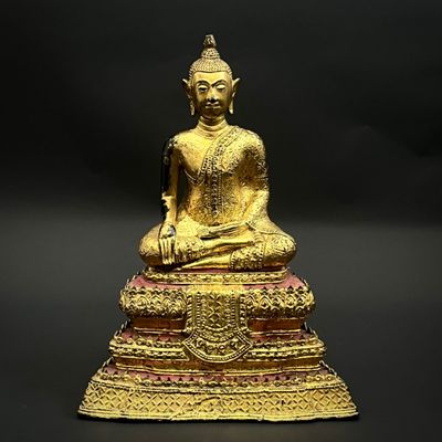 statue of a seated buddha on a pedestal with a black background