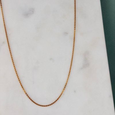 a gold chain necklace on a marble slab