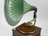 un vieux gramophone vert posé sur un socle en bois, sur fond blanc