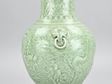 green vase with a dragon handle on a pedestal on a gray background