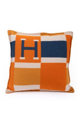un gros plan sur un coussin orange et bleu sur lequel figure la lettre h
