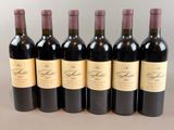six bottles of red wine lined up in a row on a table