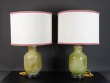 une paire de lampes vertes et roses avec des abat-jours blancs, posées sur une table noire