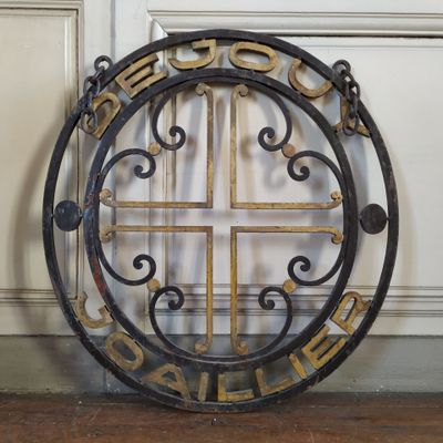 an image of a round iron sign with a cross in the center