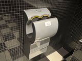 un distributeur de papier toilette dans une salle de bains au sol à carreaux