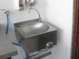 a stainless steel sink in the corner of a bathroom