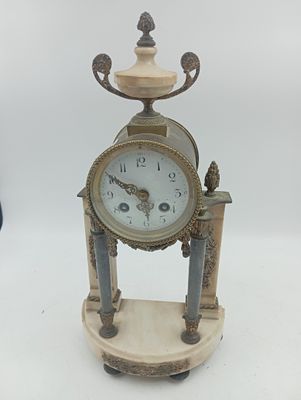 une horloge posée sur un support sur une surface blanche