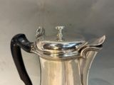 a silver coffee pot with a handle on a table