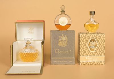 three bottles of perfume sitting on top of a table next to a box