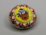 an image of a yellow and red broochle with flowers on it