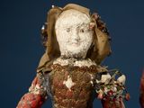 an old doll with a red dress and a brown hat