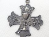 a silver cross with a sun on top of it
