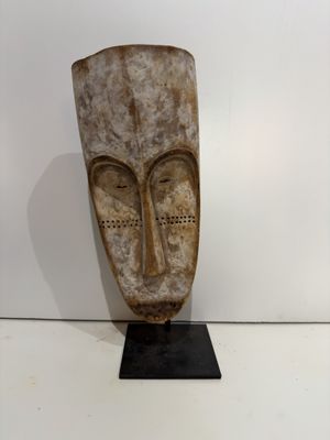 an image of a wooden sculpture of a face on a black stand