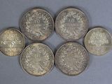 six different coins are arranged in a circle on a gray surface