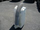 a white air conditioner sitting on the ground in a parking lot