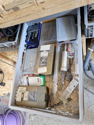un tiroir rempli d'outils divers, posé par terre