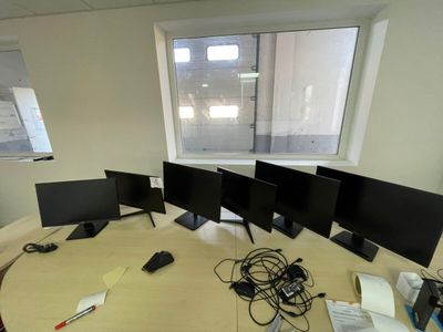 three computer monitors sitting on a table in an office