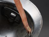 an old helmet with a leather strap hanging from it ' s side