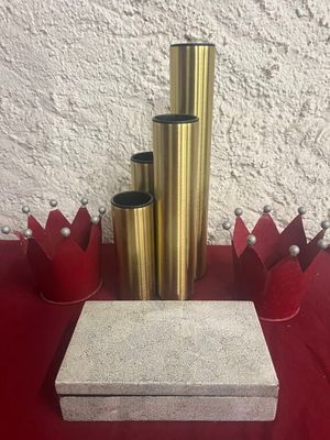 une table rouge sur laquelle sont posés des vases dorés et une boîte blanche