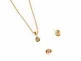 un gros plan d'un ensemble composé d'un collier et de boucles d'oreilles en or sur fond blanc