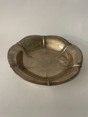 an old silver ashtray sitting on a white surface