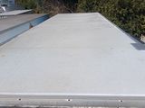 a flat roof on a flatbed trailer parked on the side of the road