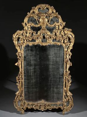 un miroir richement sculpté, doté d'un cadre doré et d'un fond noir
