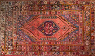 un vieux tapis persan aux motifs colorés sur fond rouge