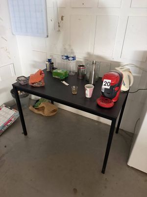 une table noire sur laquelle est posée une cafetière rouge