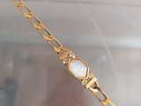 a gold bracelet that has a white stone on it