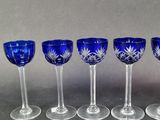 six blue glass goblets are lined up on a table