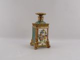 a small gold and green vase with flowers on it