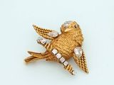une broche en forme d'oiseau dorée sur un fond blanc