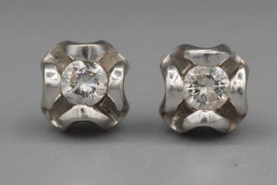 une paire de boucles d'oreilles à clous en or blanc et diamants posées sur un fond gris
